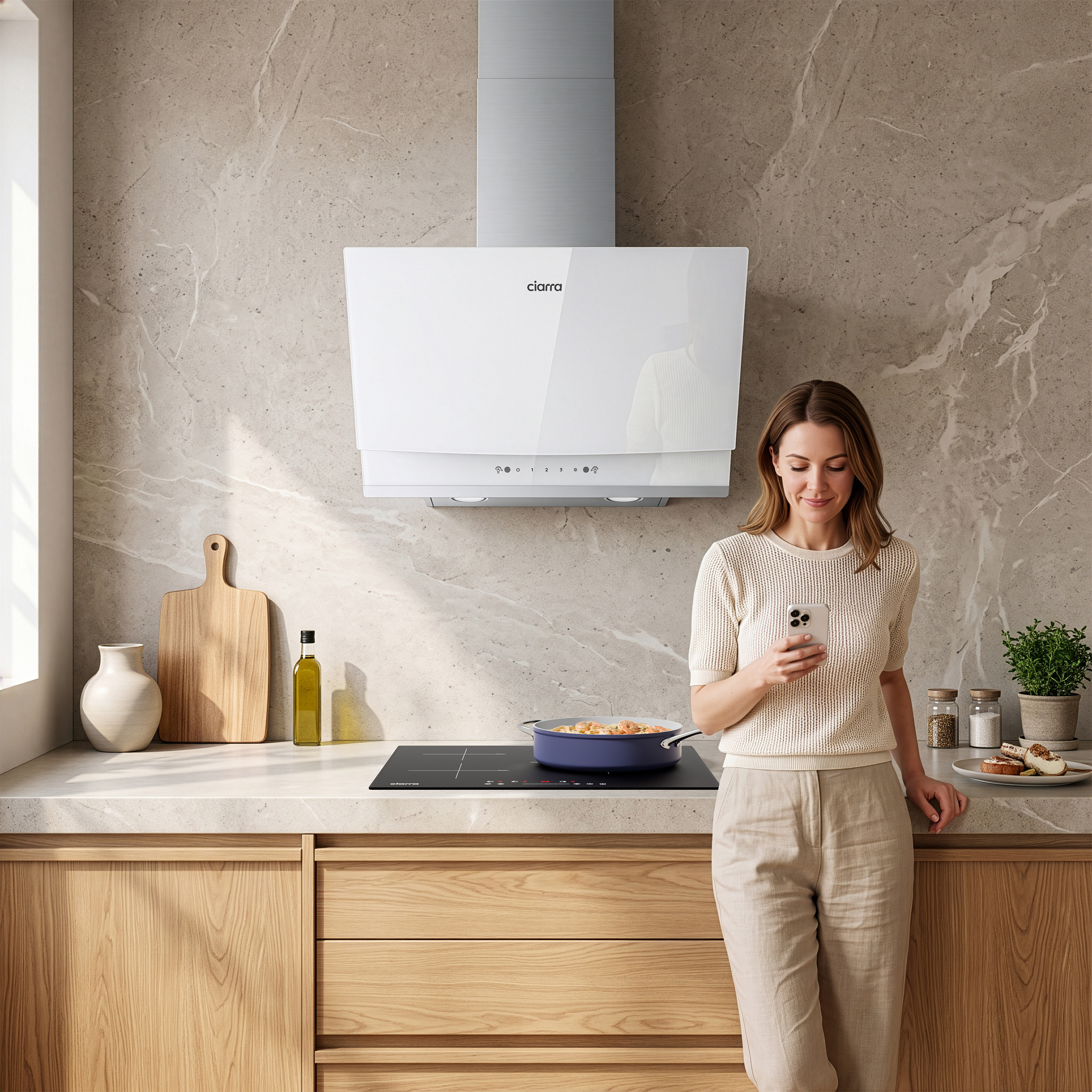 Una donna è in una cucina moderna e guarda il suo telefono. Un piano cottura a induzione è in uso.