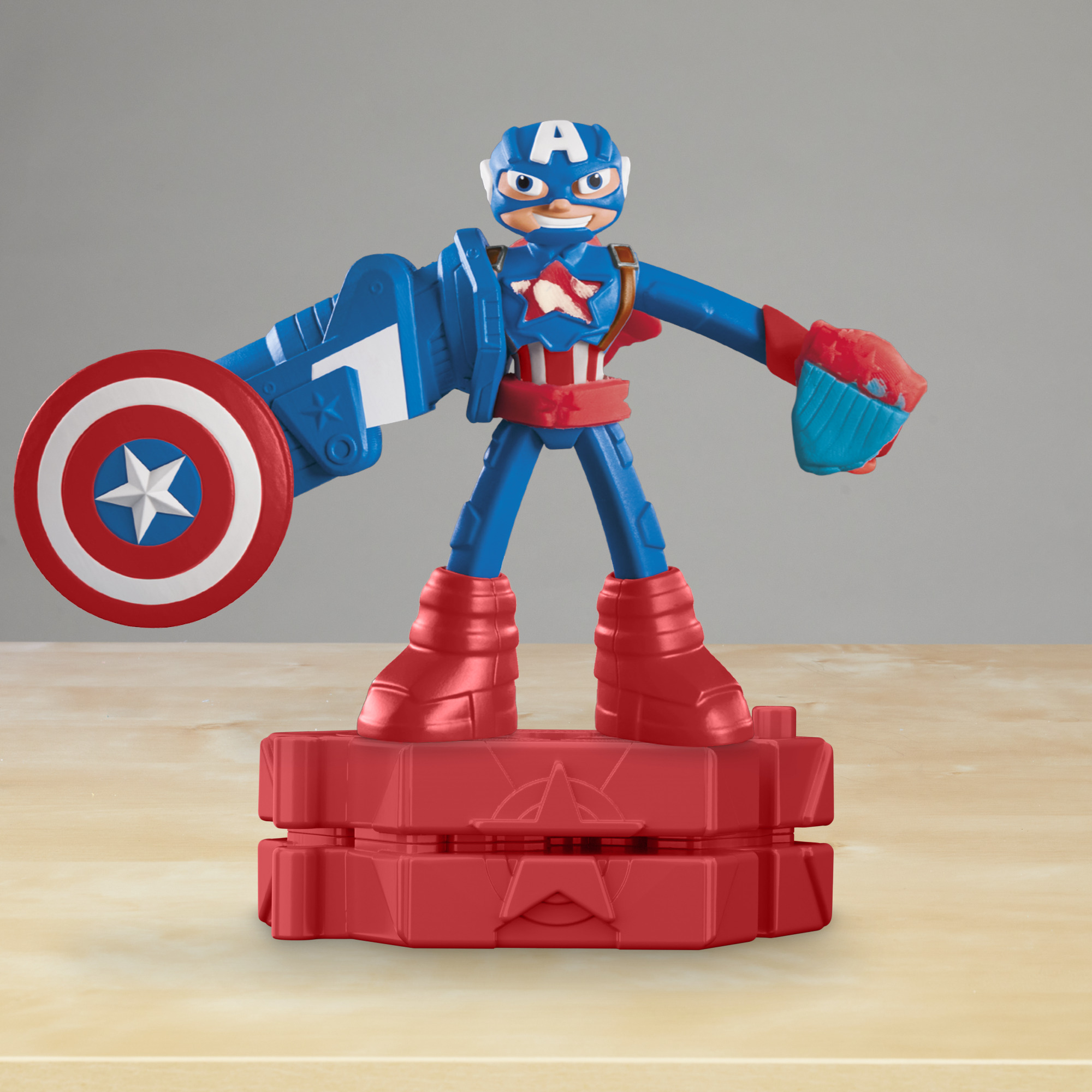 Una figura de juguete del Capitán América en rojo, azul y blanco está sobre una base roja.