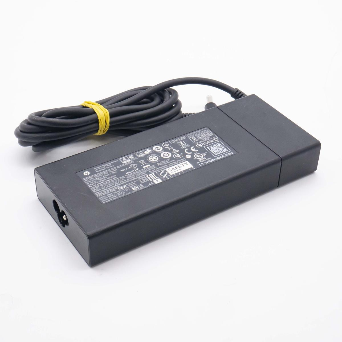 Un alimentatore nero per laptop HP con cavo nero arrotolato fissato da un elastico giallo.