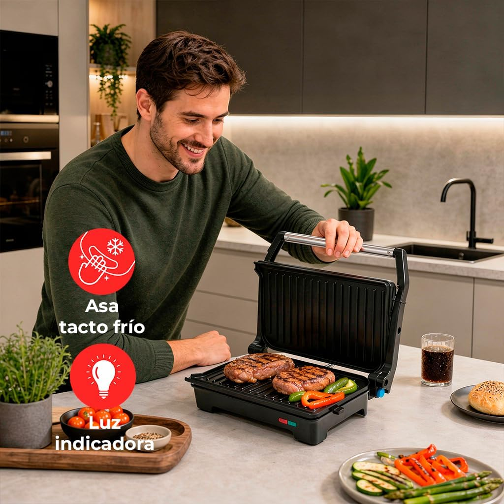 Uomo griglia bistecche e verdure su una griglia da banco in una cucina moderna.