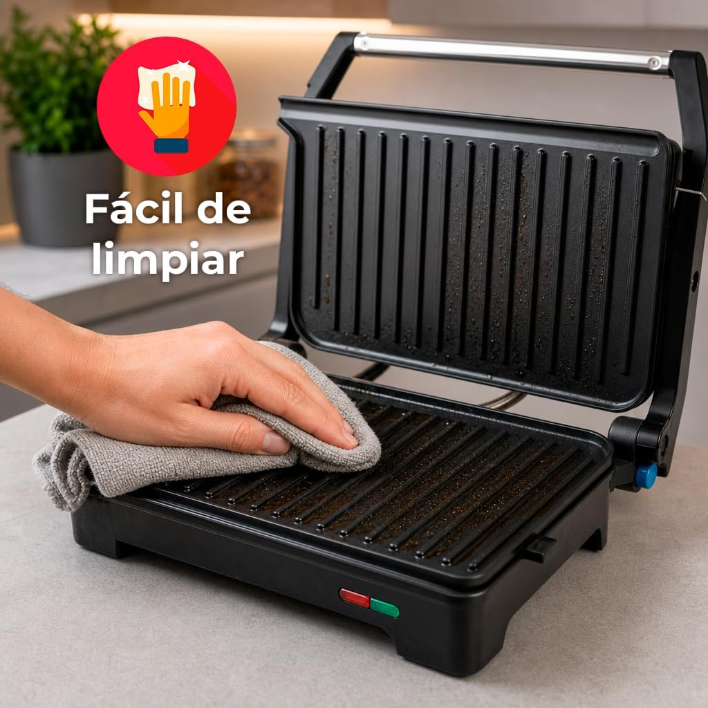 Una mano pulisce una piastra grill nera con un panno grigio.