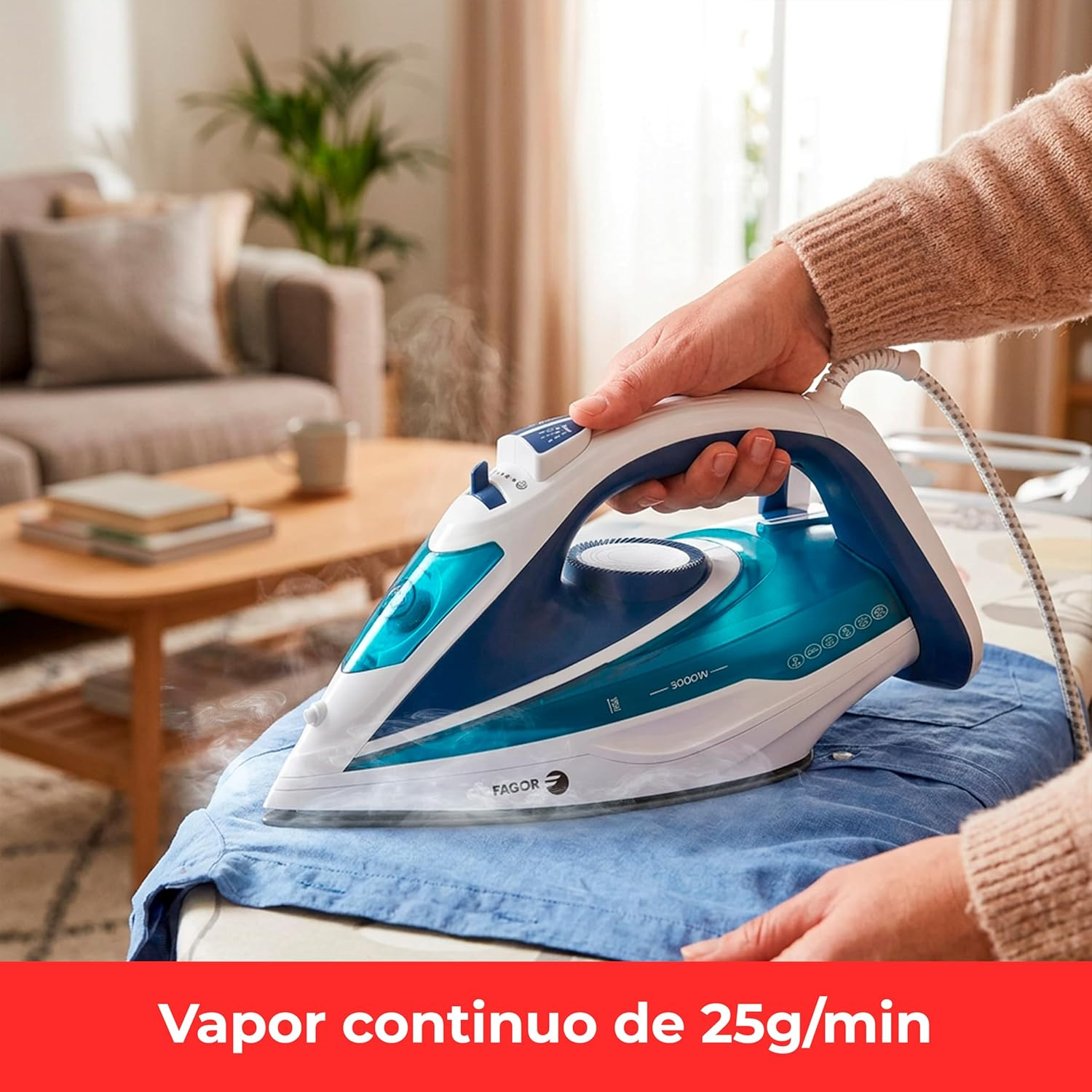 Una mano usa un ferro da stiro blu e bianco per stirare una camicia blu.