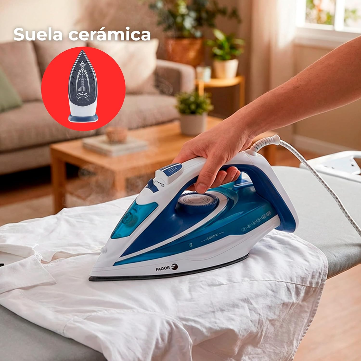 Una mano usa un ferro da stiro blu e bianco per stirare una camicia bianca su un asse da stiro.