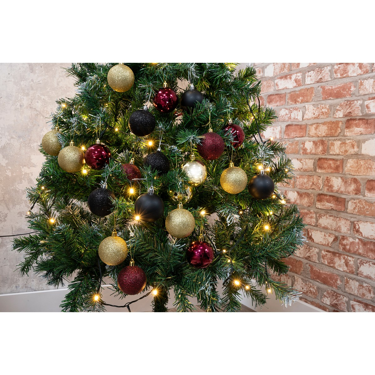 A Christmas tree decorated with gold, red, and black baubles and lights.
