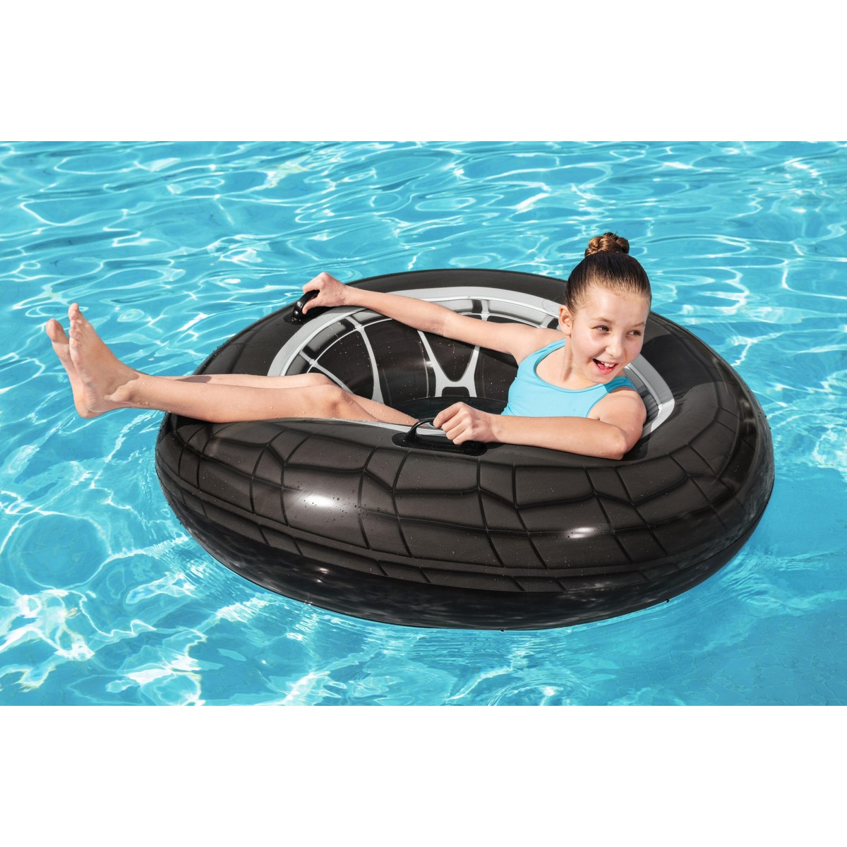 A girl in a blue swimsuit floats on a tire-shaped inner tube in the water.