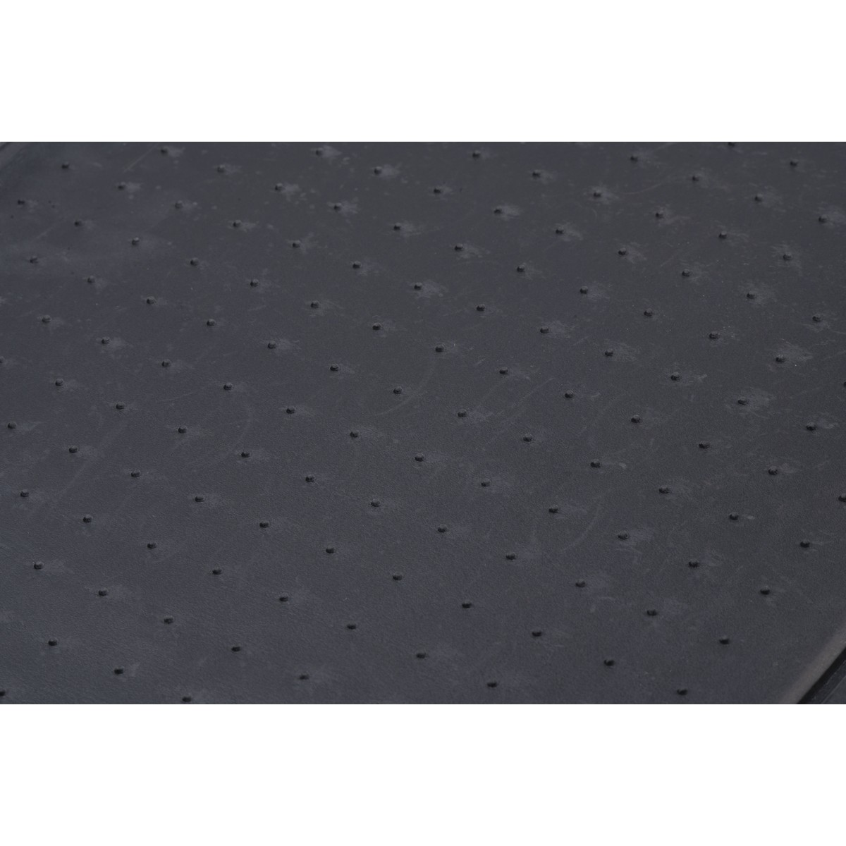 Dark grey surface with a pattern of small, raised dots.