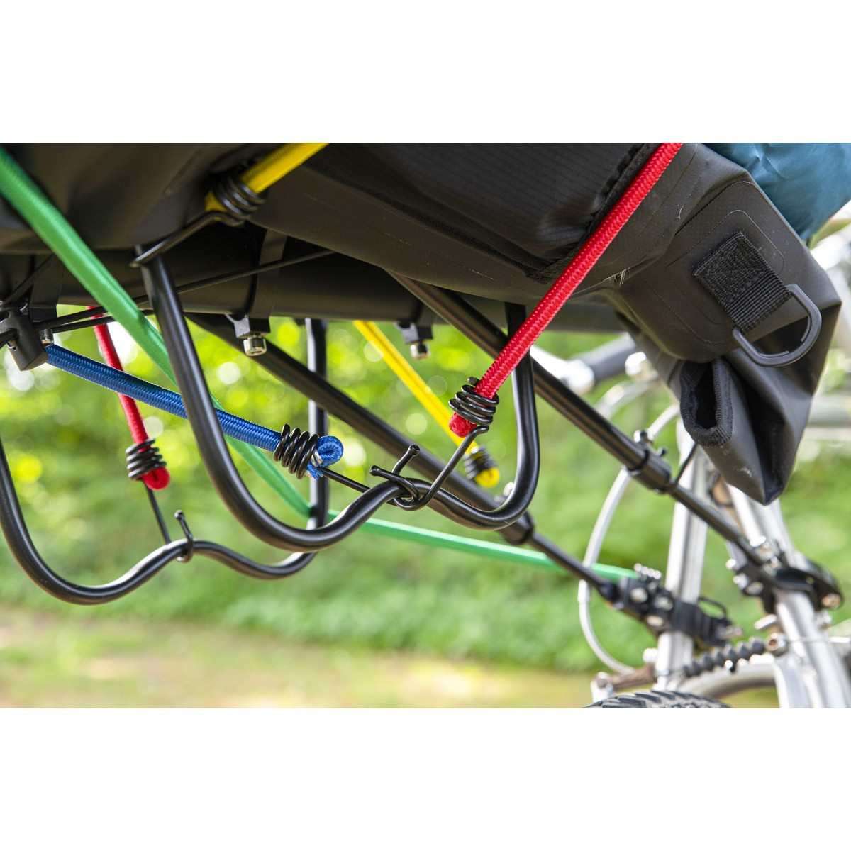 Fietsendrager met kleurrijke elastieken in groen, blauw, rood en geel.