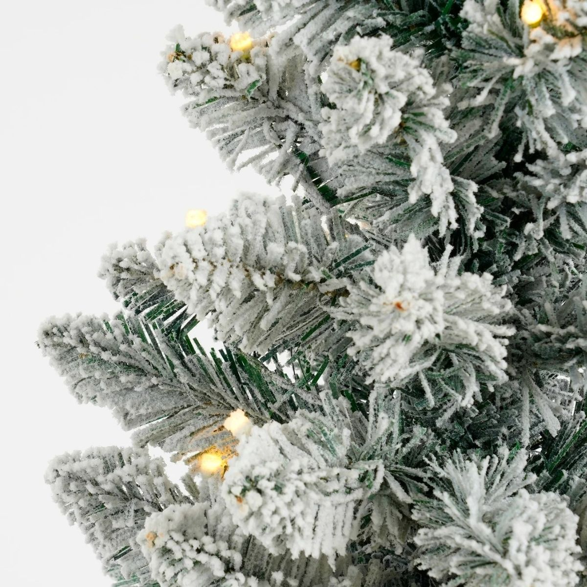 Close-up of a flocked artificial Christmas tree with lights.