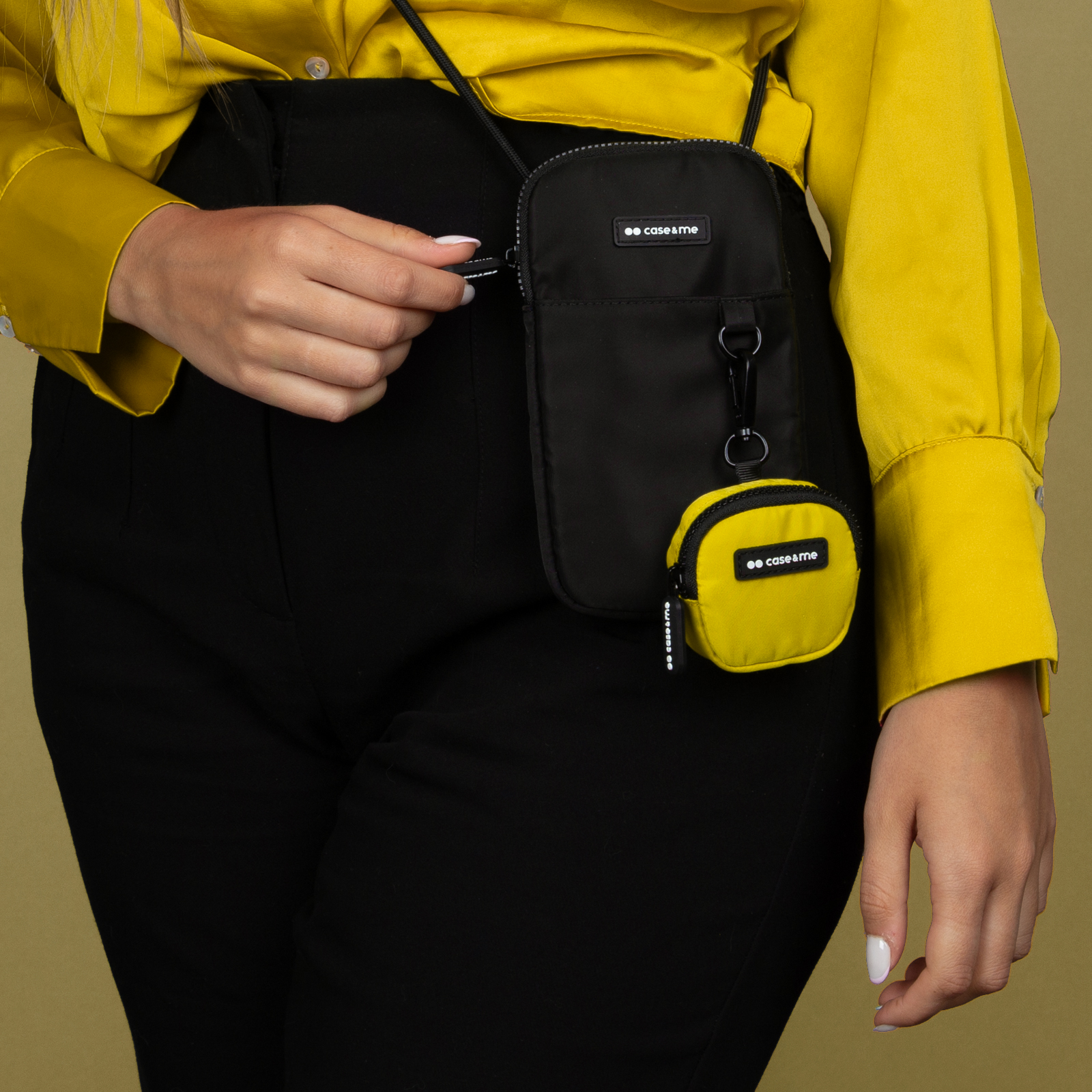 Una persona de amarillo y negro lleva un bolso negro pequeño con un monedero amarillo.