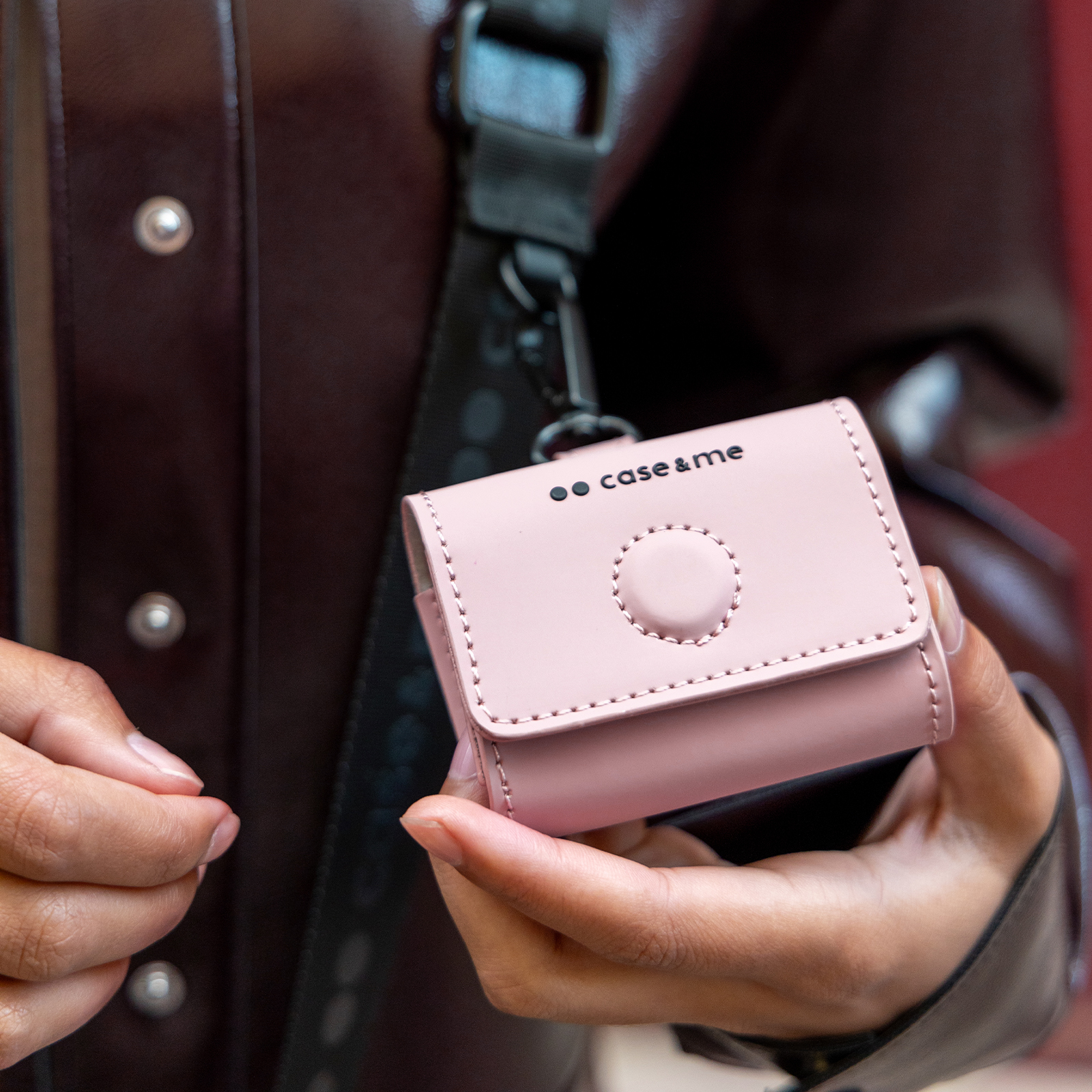 Una persona sostiene un estuche rosa con la marca "case & me".