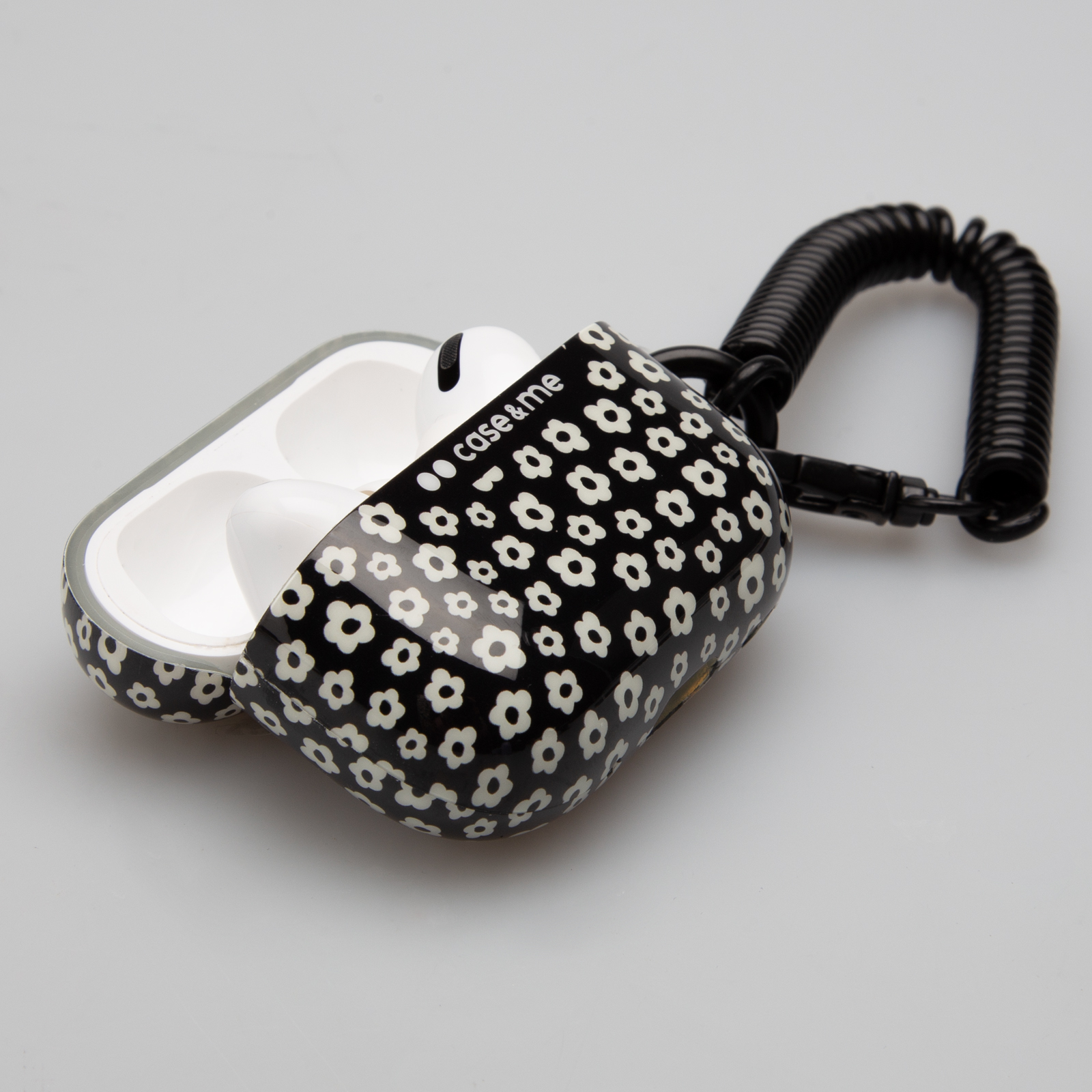 Un estuche negro con estampado floral para auriculares, abierto, con correa en espiral.