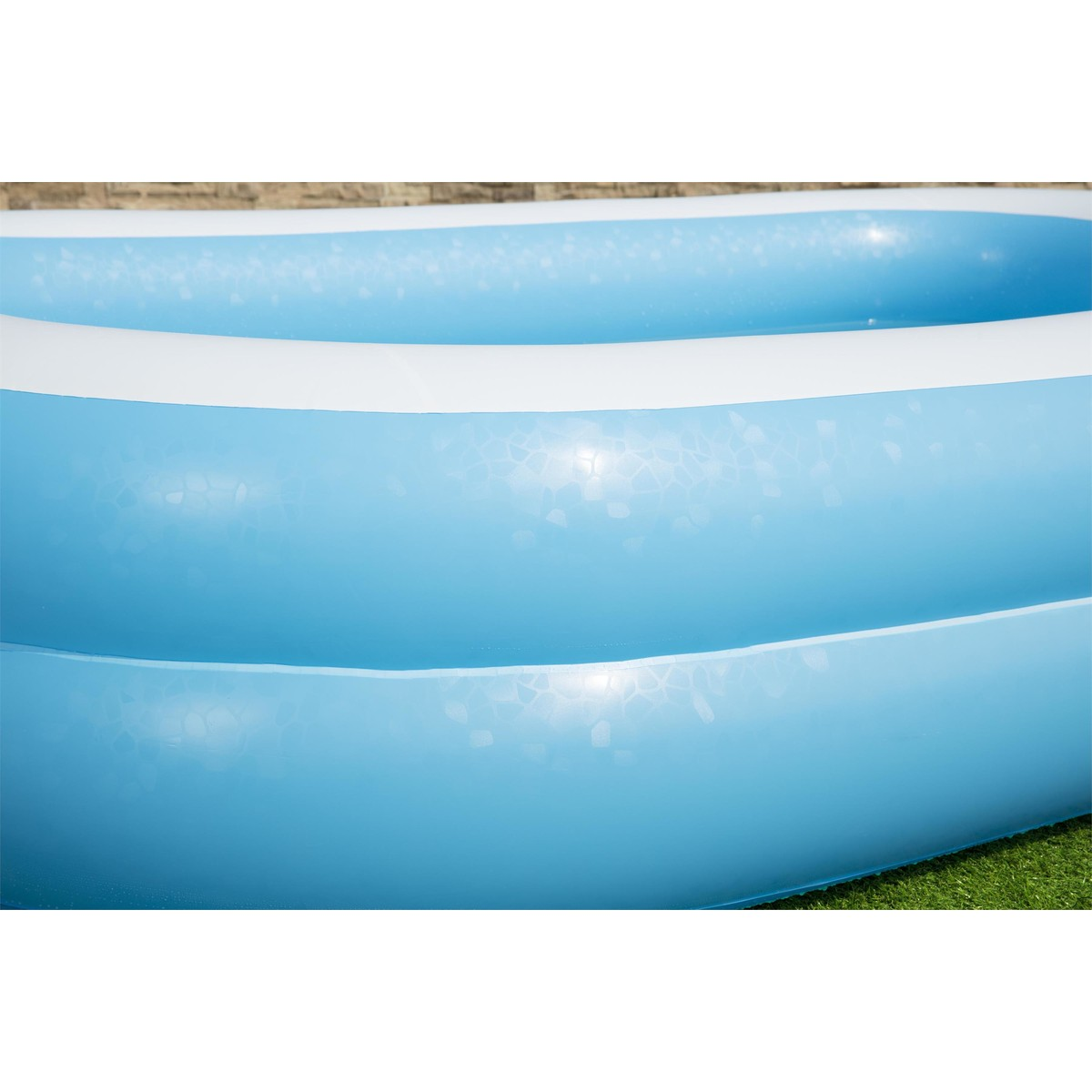 Una piscina gonfiabile con acqua blu e anelli bianchi.