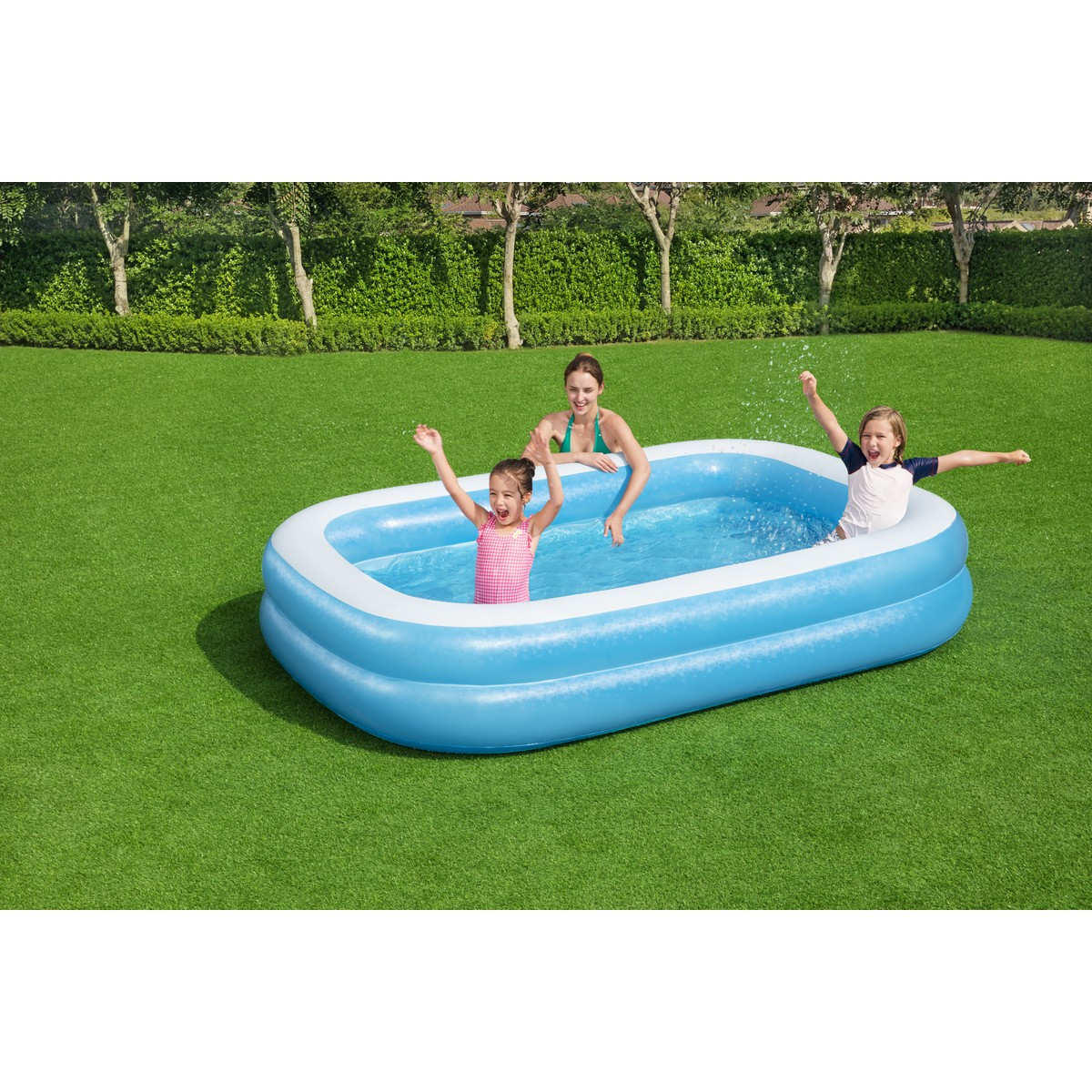 Una donna e due bambini sguazzano in una piscina gonfiabile su un prato.