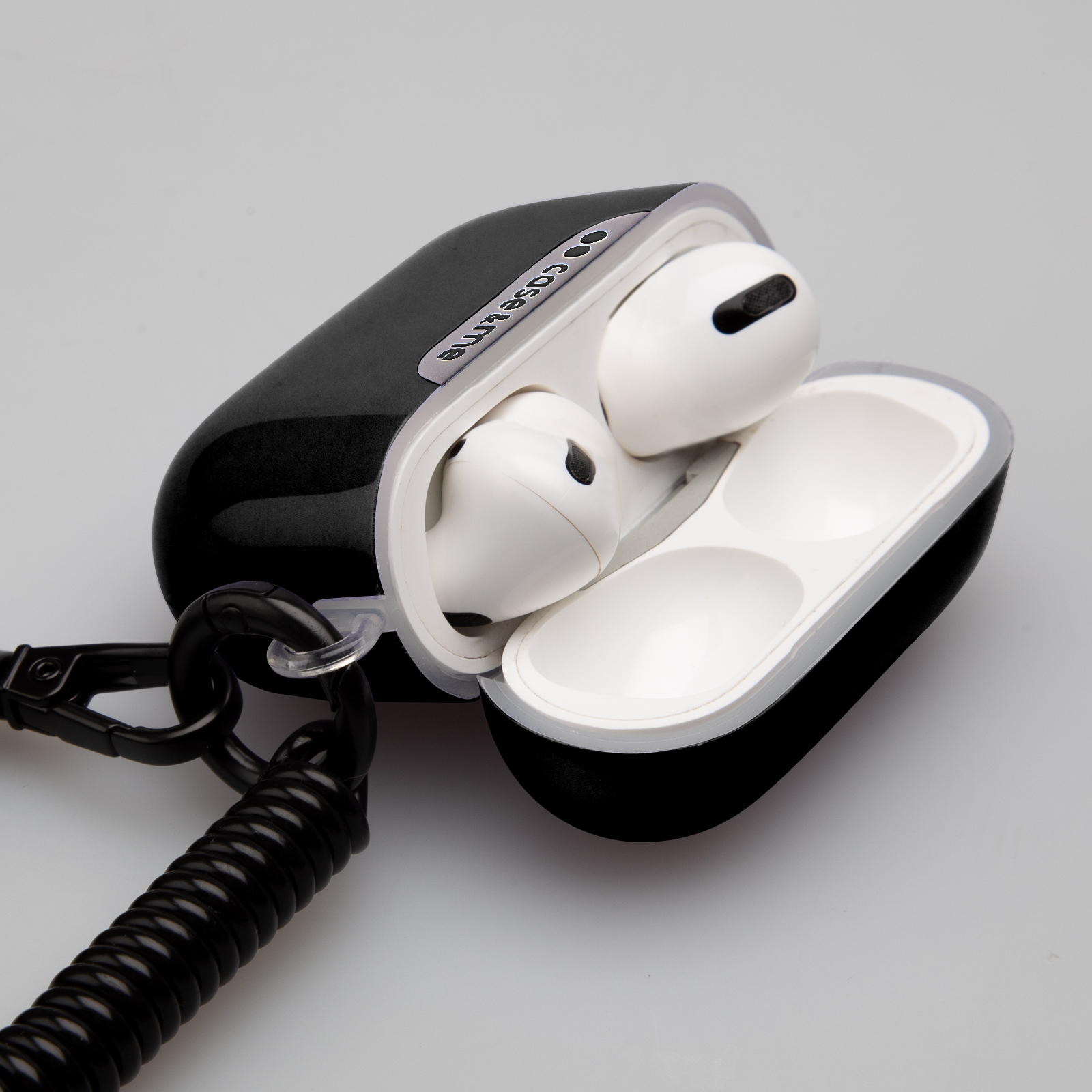 Un estuche de carga negro con auriculares blancos y un cable en espiral.