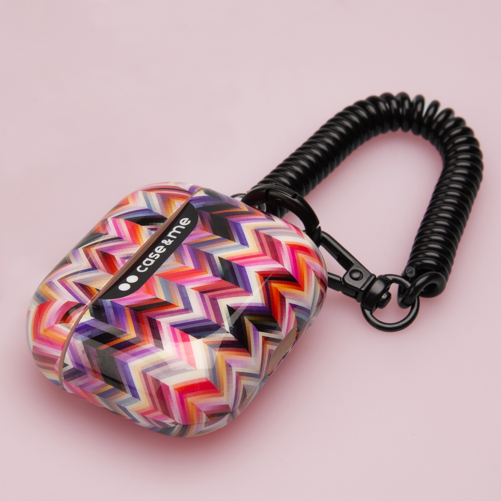 Funda geométrica colorida con cordón en espiral negro y mosquetón sobre fondo rosa.