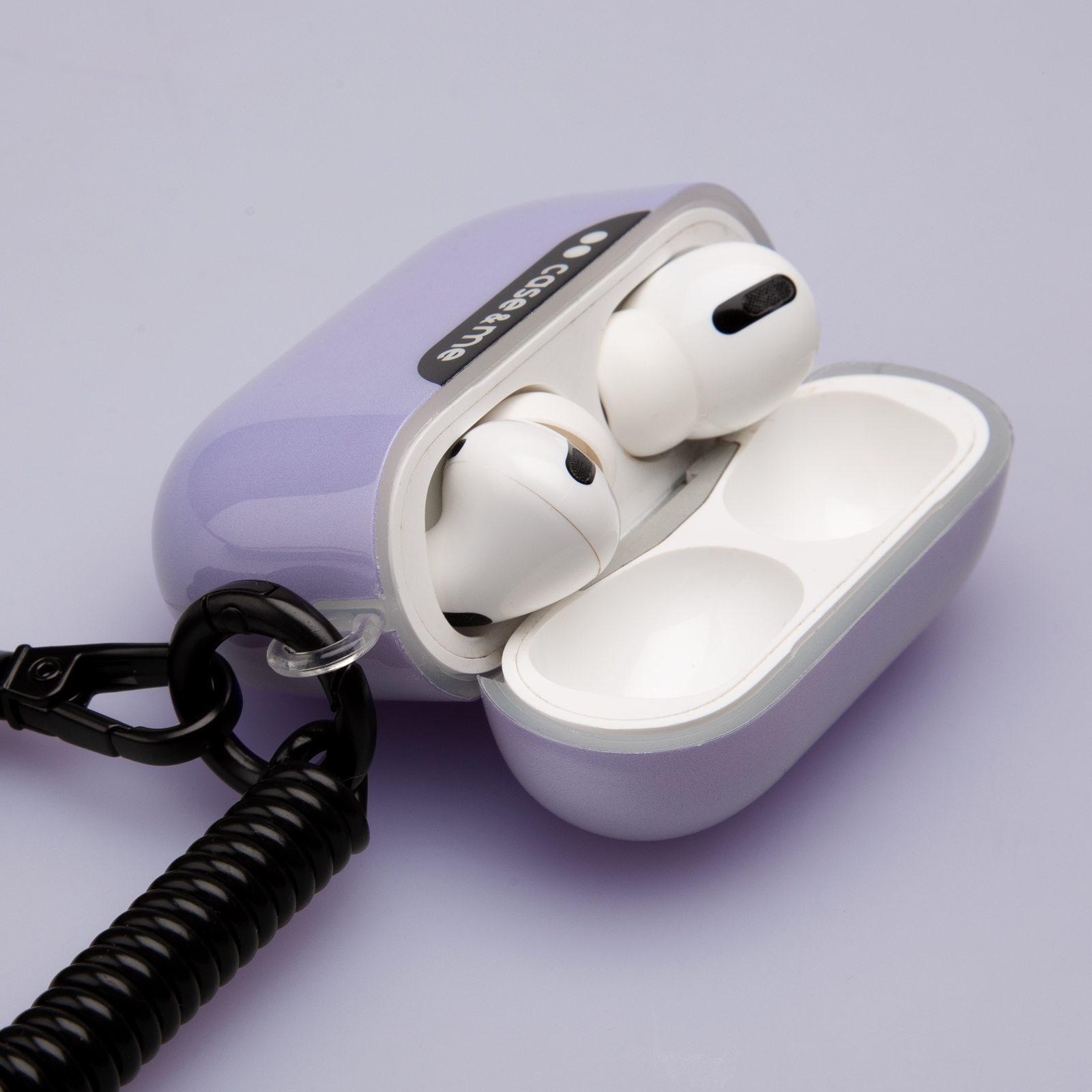 Un estuche morado para AirPods con AirPods blancos y un cordón enrollado negro.