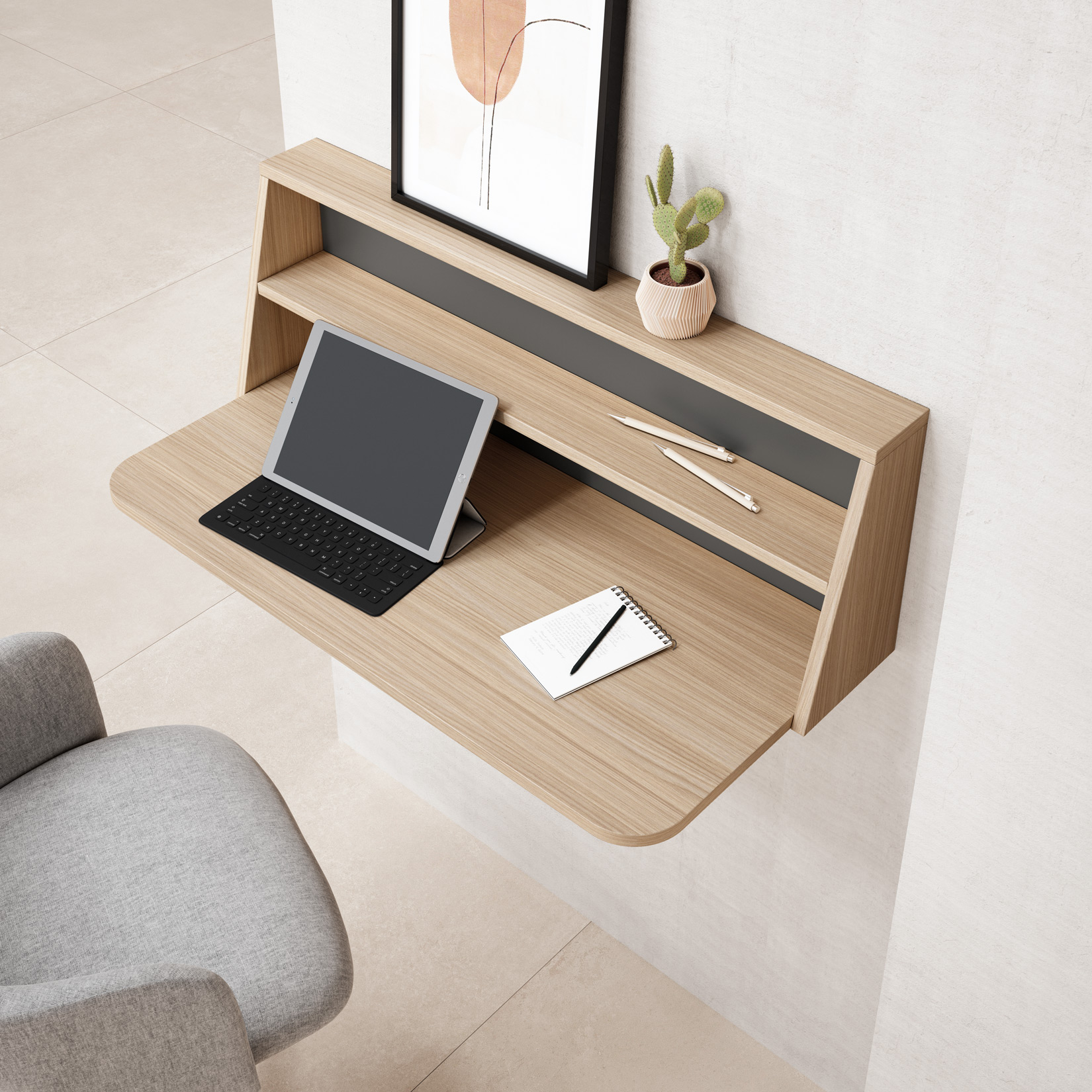 Un escritorio flotante de madera con tablet, teclado, libreta, bolígrafos y cactus.