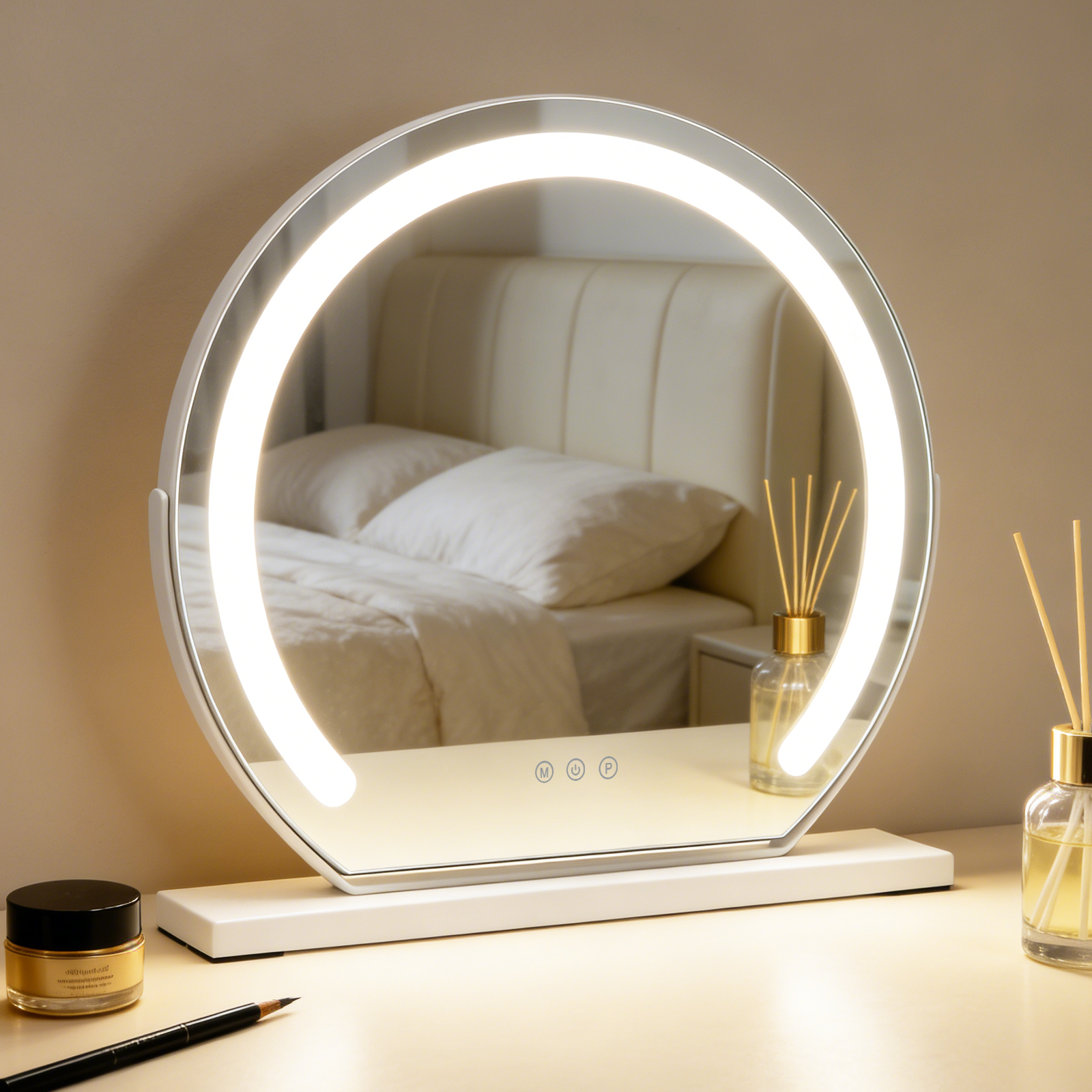 Un espejo de maquillaje iluminado está sobre una mesa frente a una cama. Un frasco de cosmético y un lápiz están delante.