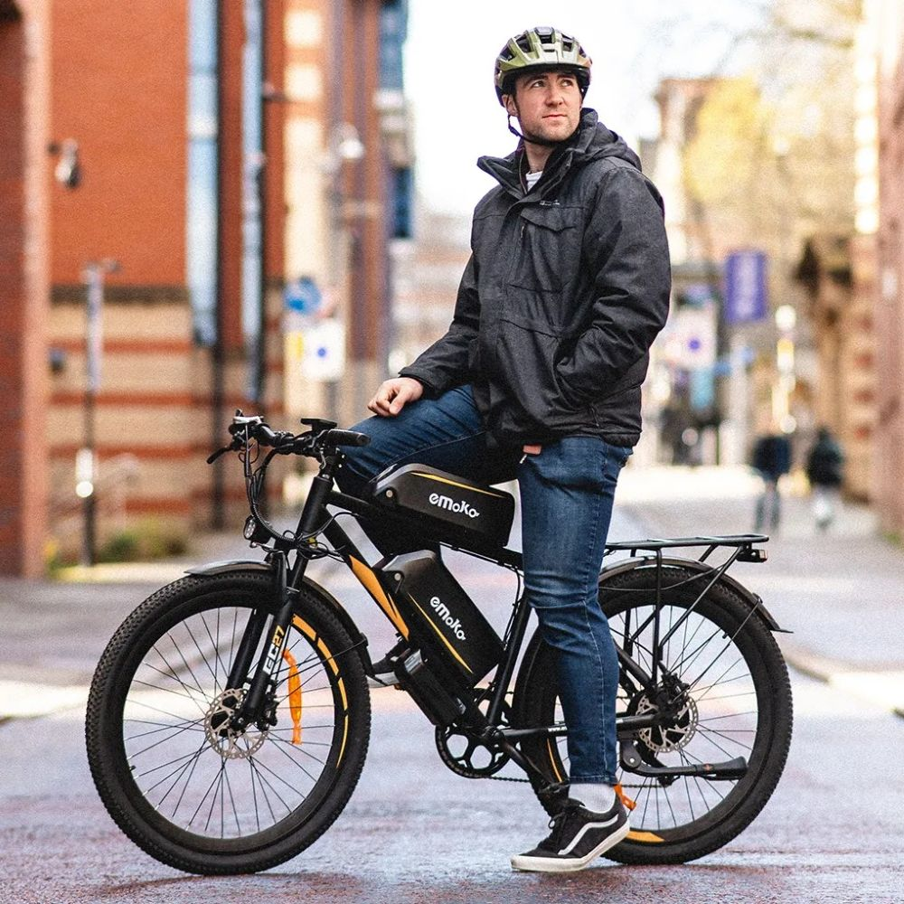 Un uomo con casco siede su una bici elettrica in una strada cittadina.
