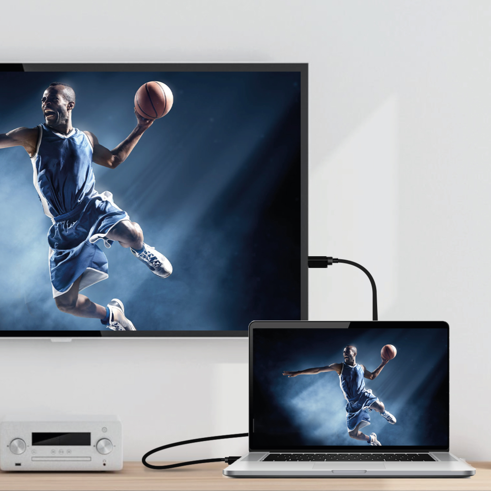 Un jugador de baloncesto salta con un balón en un portátil y pantalla de TV.