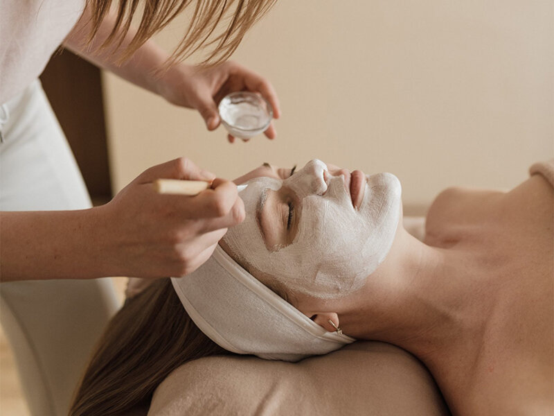 Una persona recibe una mascarilla facial aplicada por un profesional.