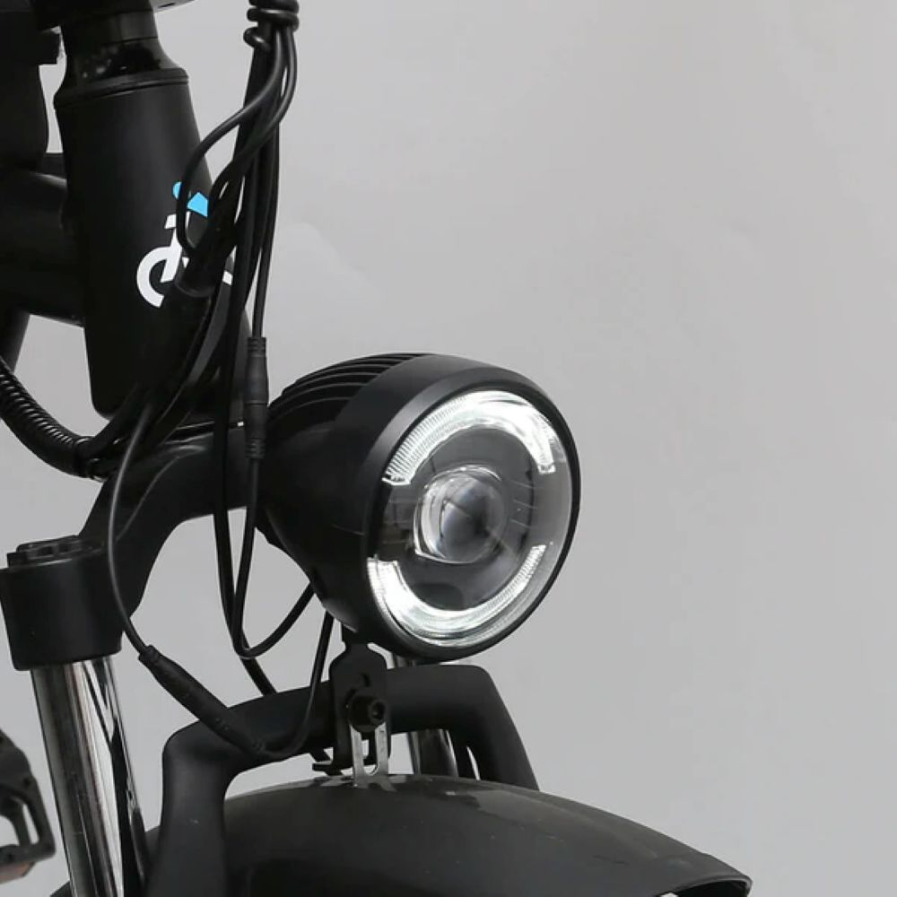 Primo piano di un faro rotondo nero per bicicletta con un alone a LED bianco.