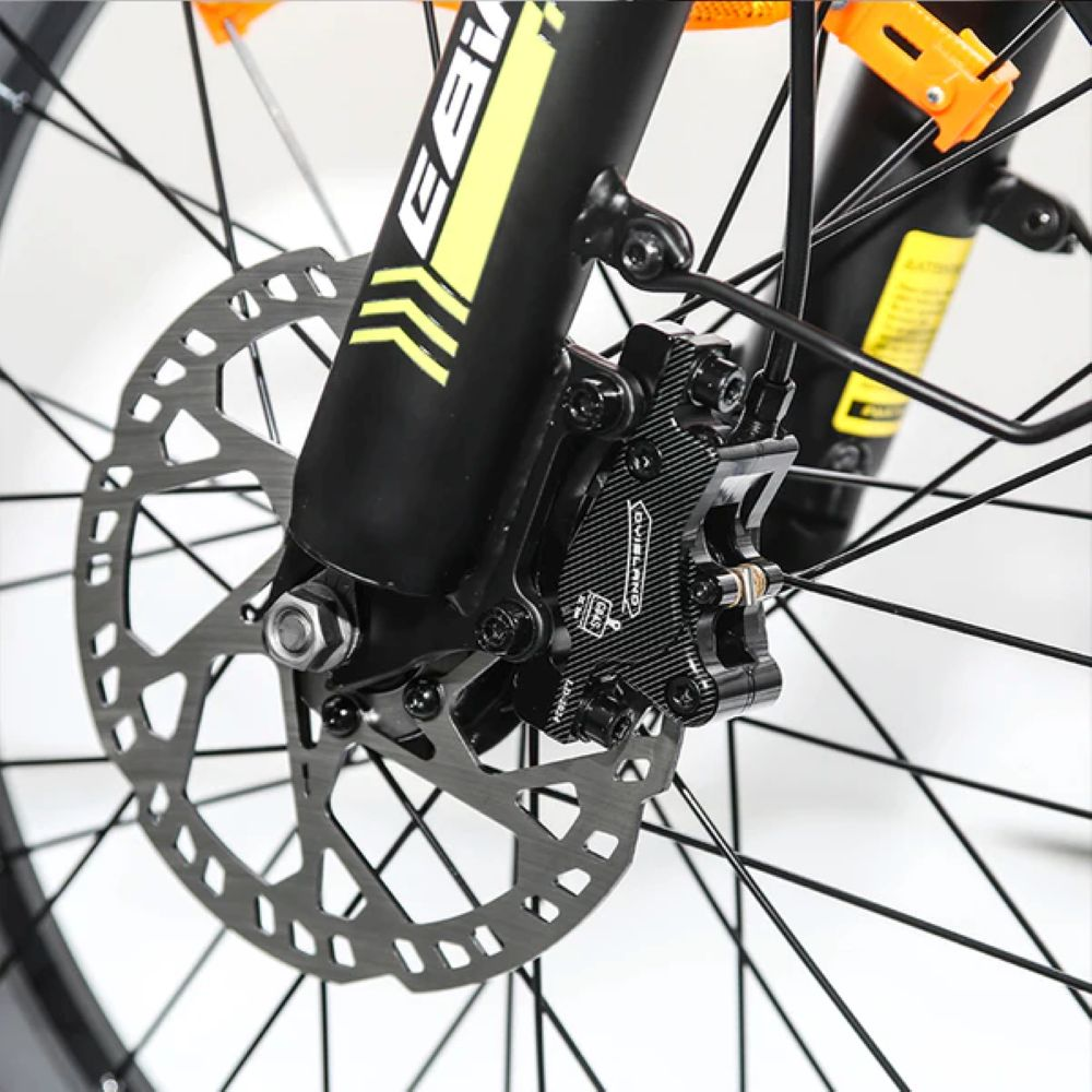 Primo piano di un freno a disco per bicicletta con pinza nera e accenti gialli.