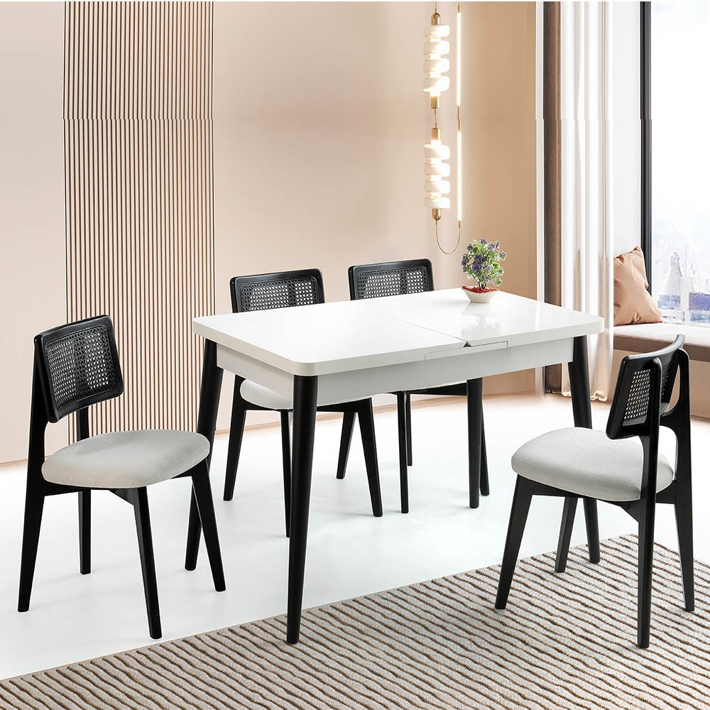 Modern beyaz yemek masası, rattan sırtlı ve açık renkli oturaklı dört siyah sandalye ile.