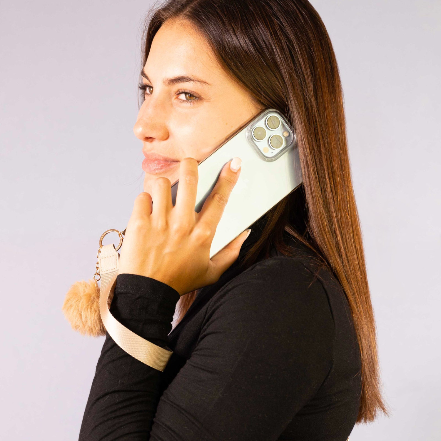 Mujer con camisa negra hablando por teléfono con llavero peludo.