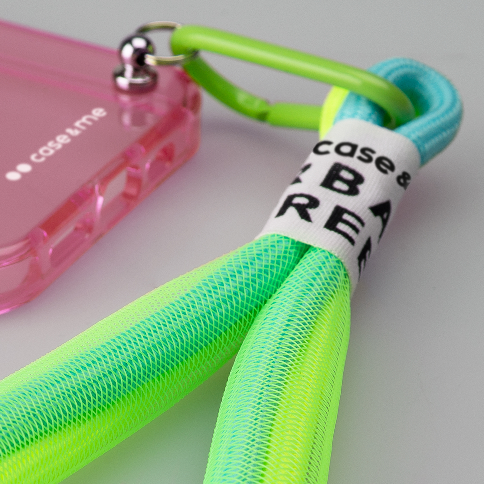Una funda de teléfono rosa con correa y cordón verde neón.
