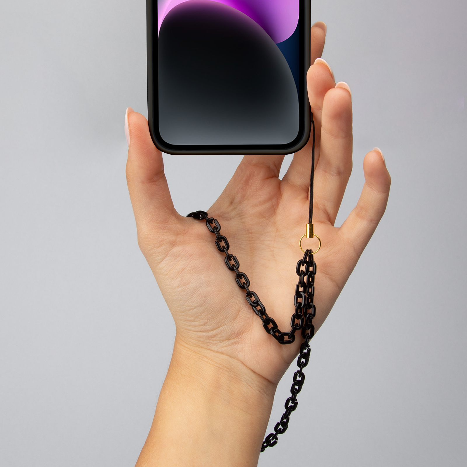 Una mano sostiene un smartphone con una cadena negra.
