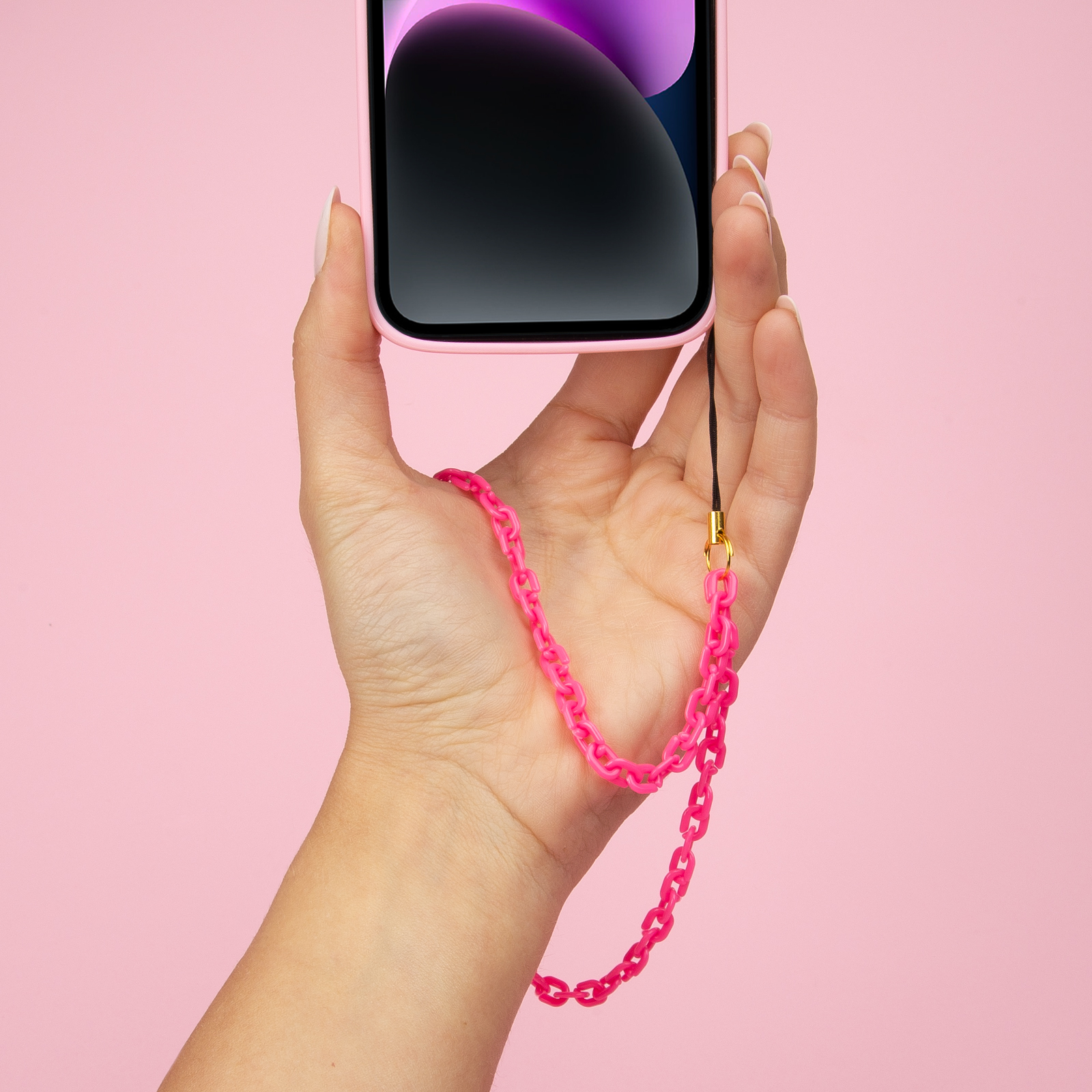 Una mano sostiene un teléfono rosa claro con una cadena rosa brillante.