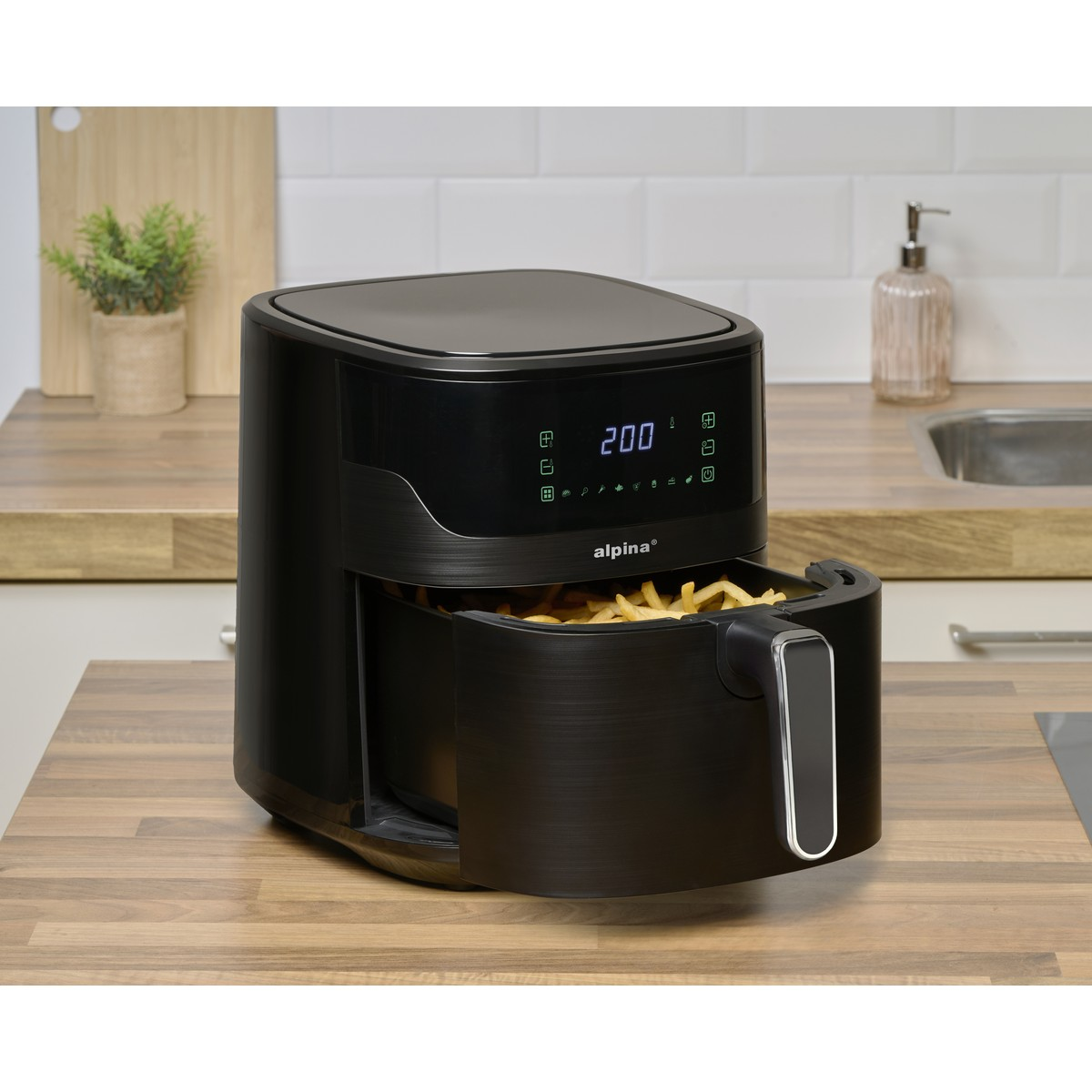 A black air fryer filled with french fries sits on a wooden counter. Digital display shows 200.