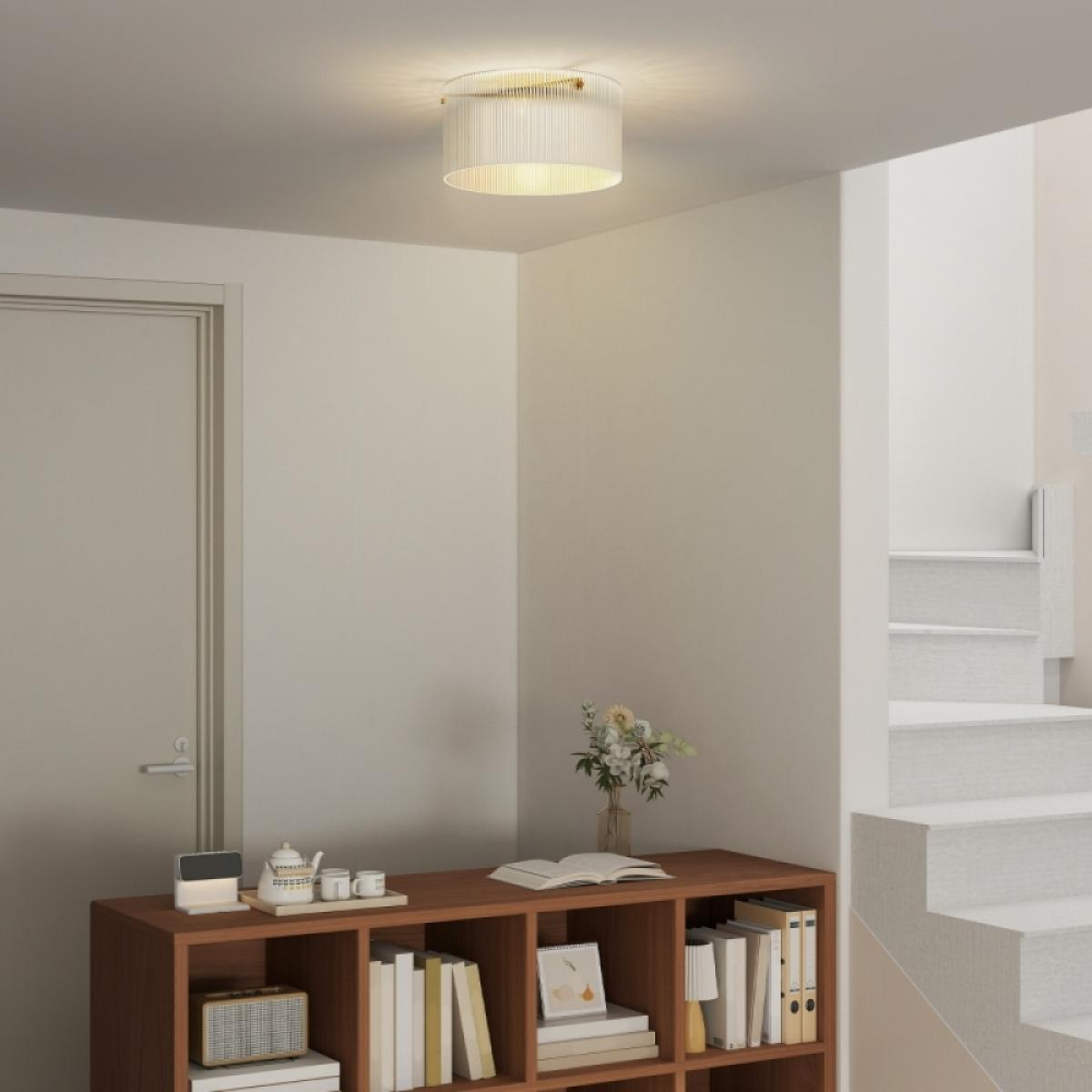 Ein Flur mit Tür, Bücherregal und Treppe. Eine Deckenleuchte beleuchtet den Raum.