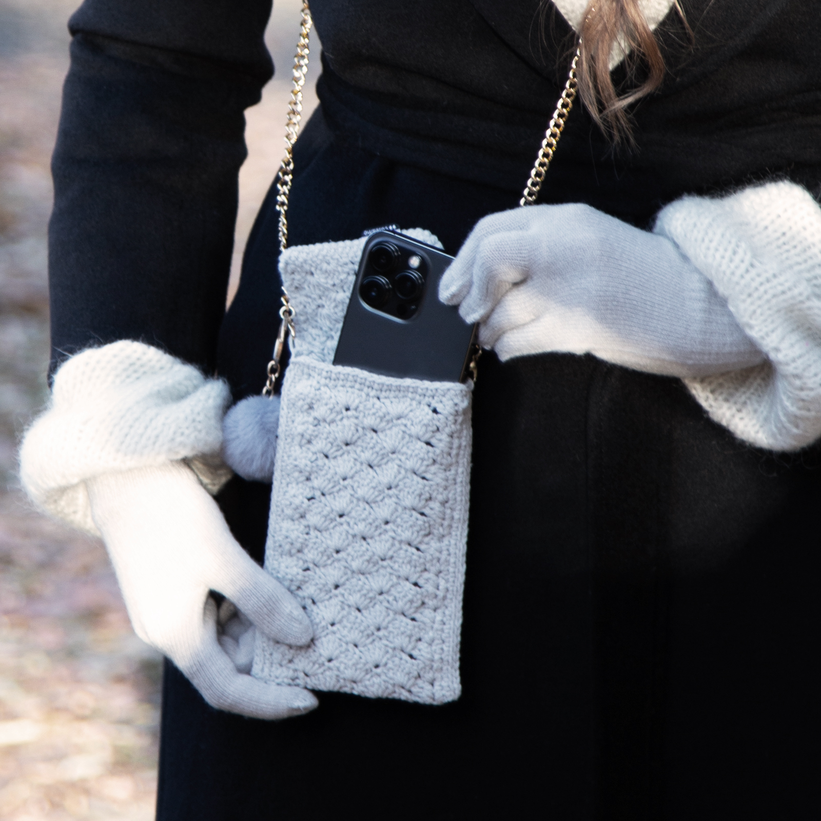 Una persona con guantes grises claros mete un smartphone en un bolsillo de punto.