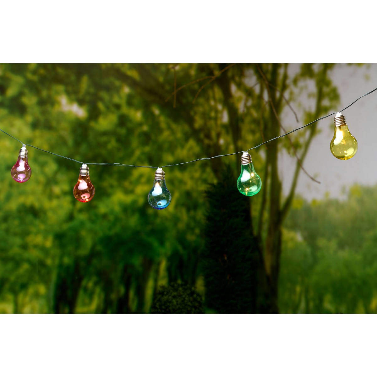 A string of colorful lights hangs outdoors against a blurred green background.
