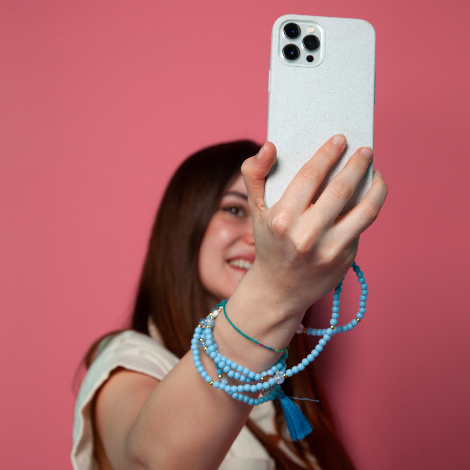 Una mujer se toma una selfie con una funda de teléfono azul claro sobre fondo rosa.