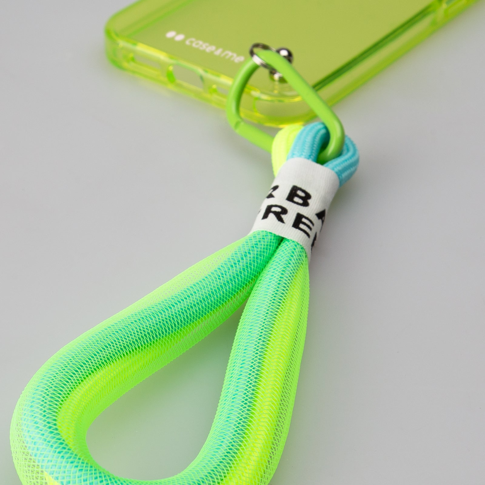 Una funda de teléfono verde neón con correa colorida y un mosquetón.