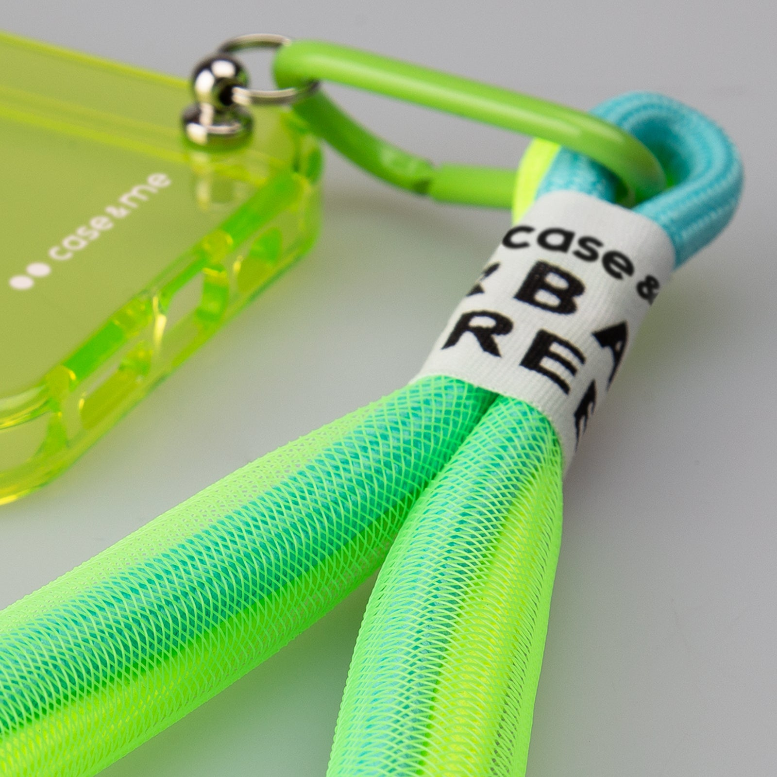 Una funda de teléfono verde neón con un cordón de material de malla azul claro y verde neón.