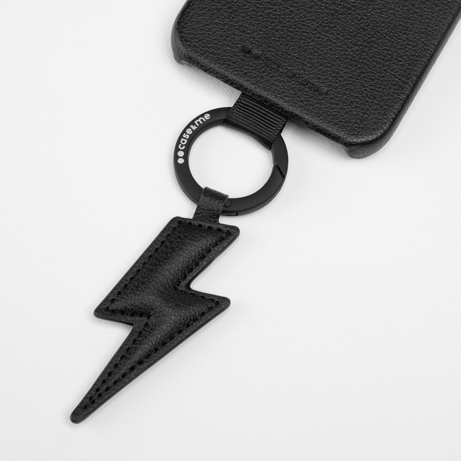 Colgante negro de cuero con forma de rayo en una funda de teléfono con anilla negra.