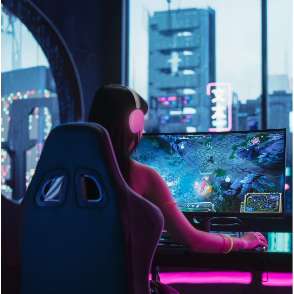 Eine Frau mit Kopfhörern spielt ein Videospiel auf einem großen Monitor in einem dunklen Raum.