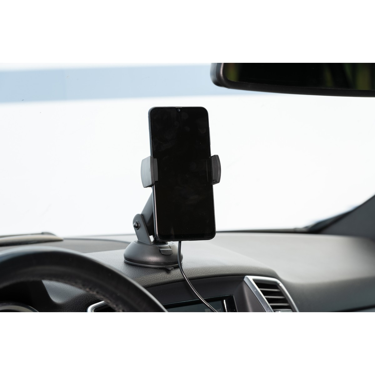Support de téléphone avec téléphone noir sur tableau de bord de voiture, près volant.