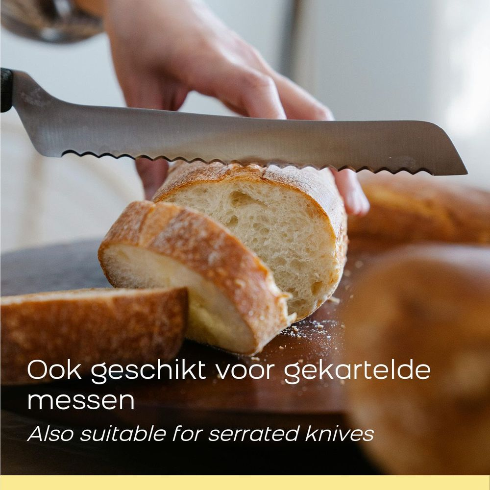 Eine Hand schneidet mit einem Brotmesser ein frisch gebackenes Brot.