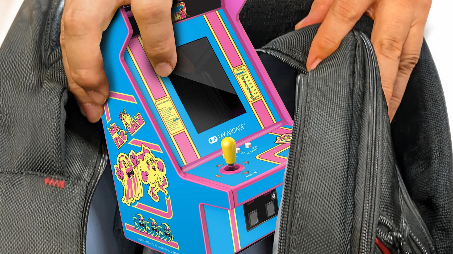 Una persona mette una sala giochi arcade blu Ms. Pac-Man in una borsa nera.