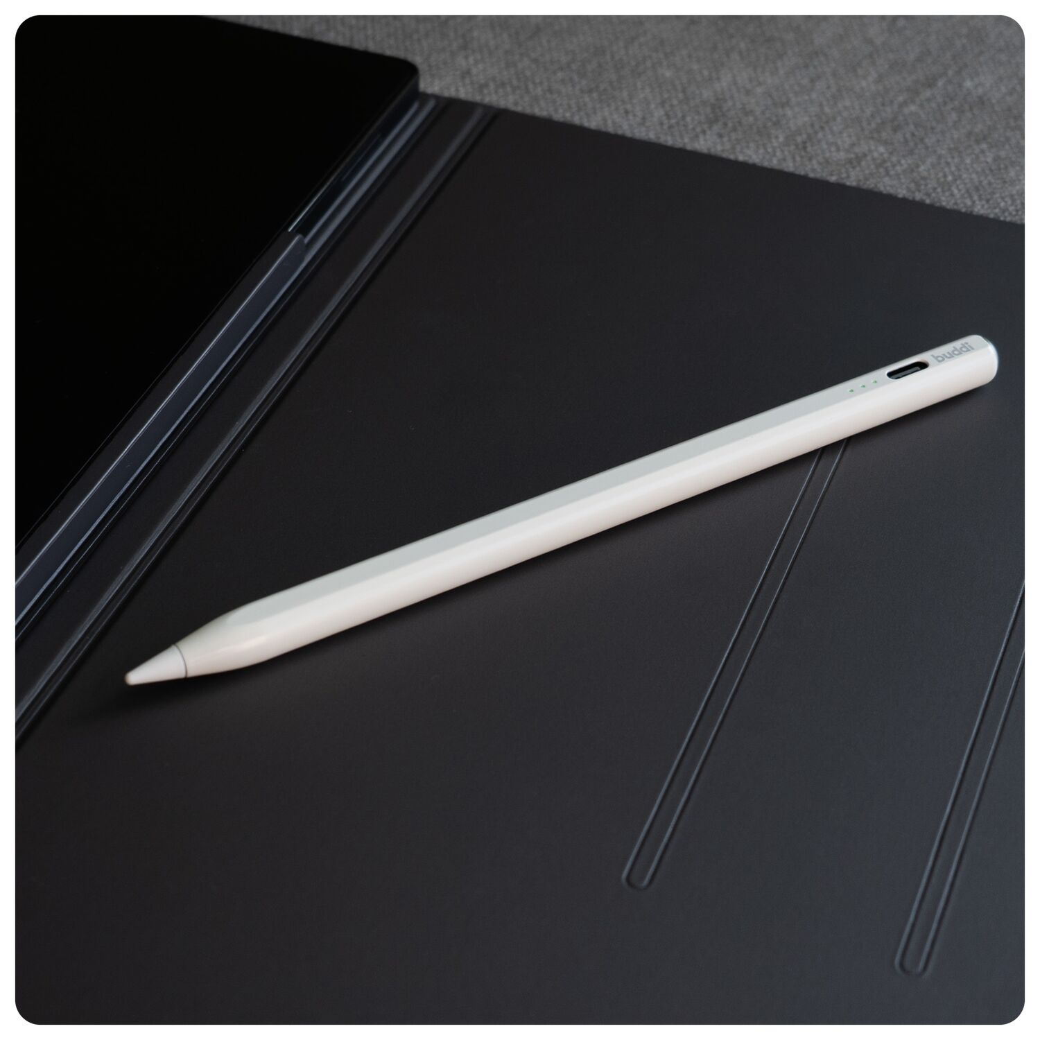 Een witte stylus ligt op een zwarte hoes naast een zwarte tablet.