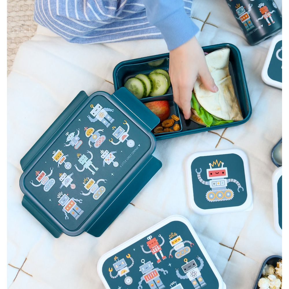 Ein Kind bereitet eine Lunchbox mit Sandwiches, Gurken, Obst und Nüssen vor.