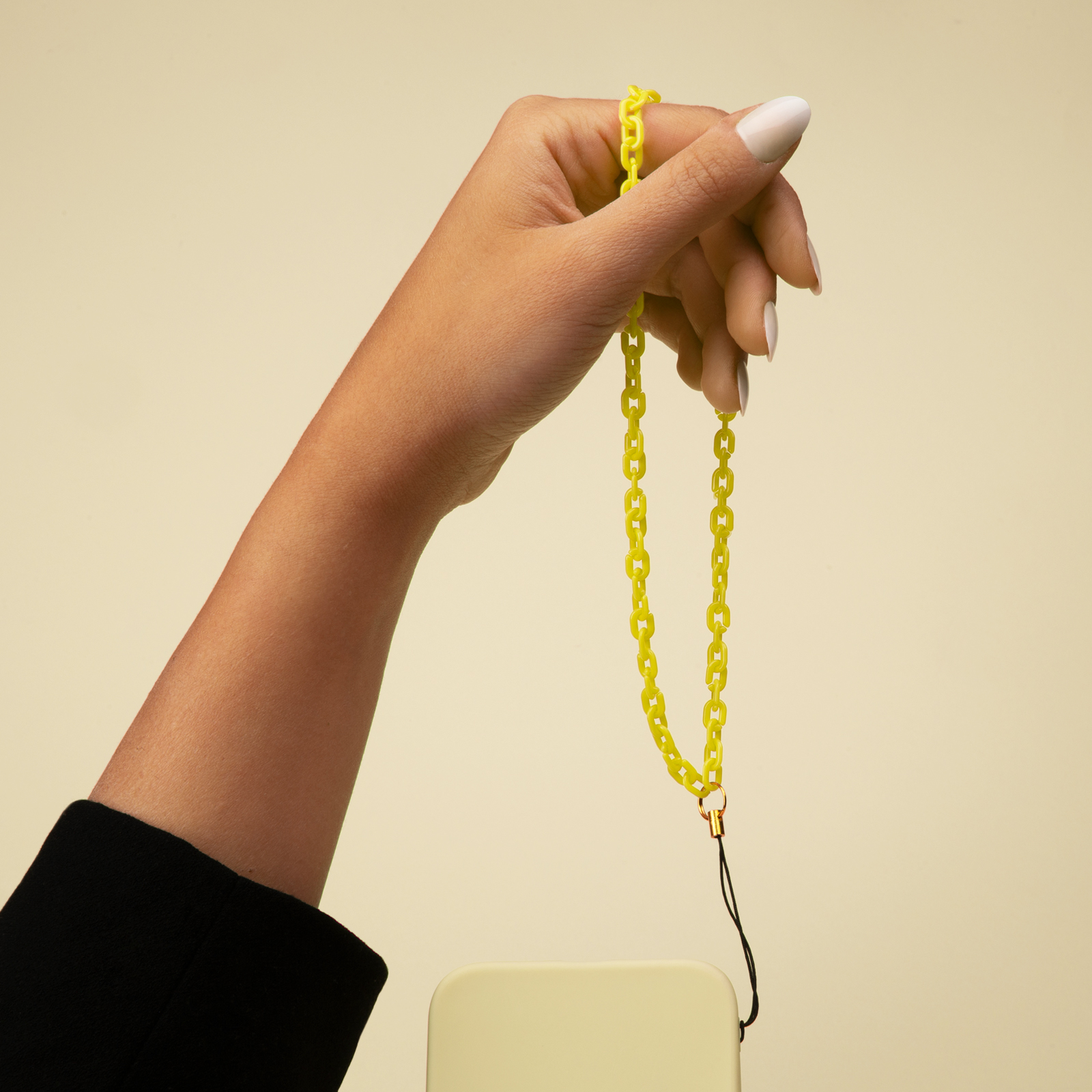 Una mano sostiene un collar de cadena amarillo con un teléfono.
