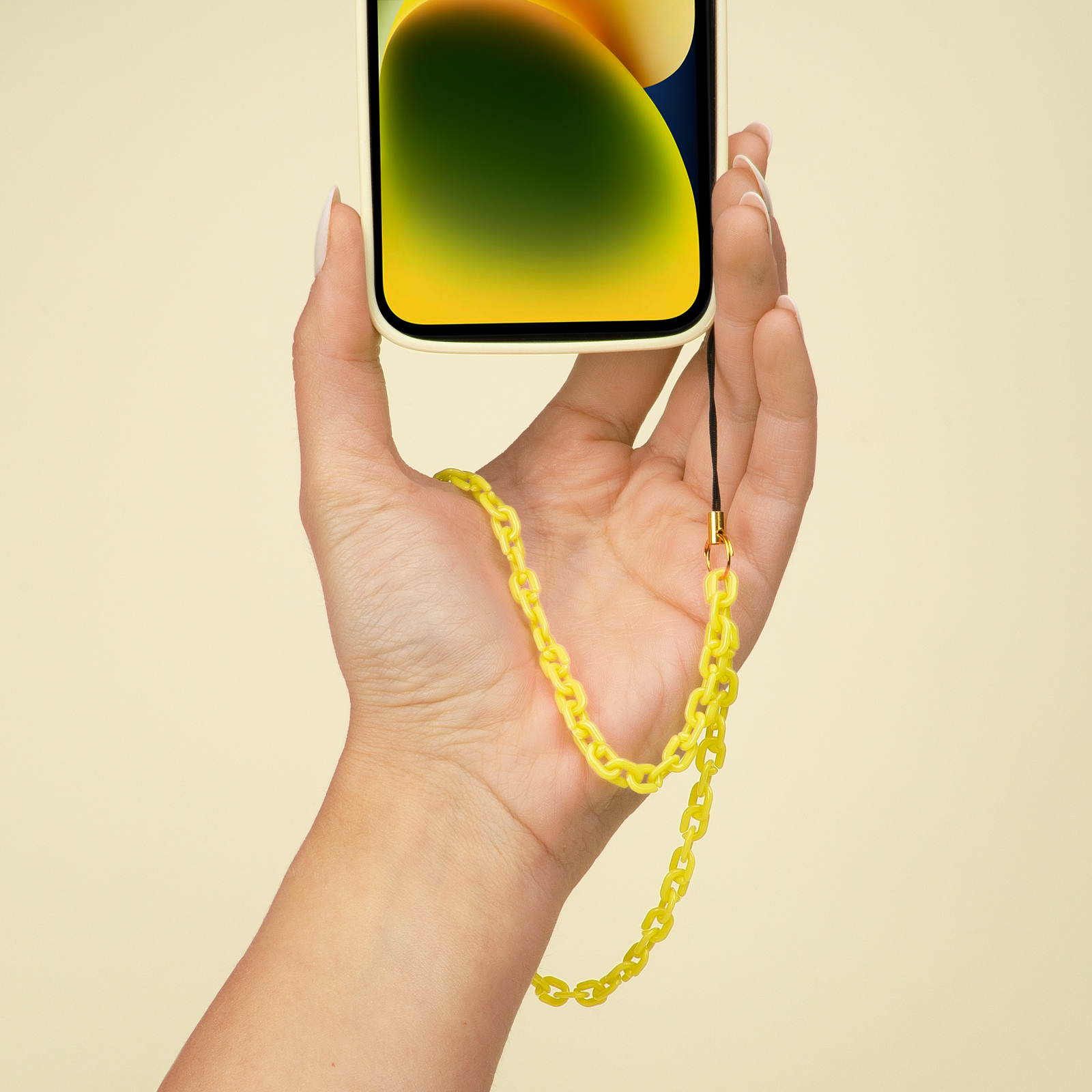 Una mano sostiene un teléfono amarillo claro con una cadena amarilla.