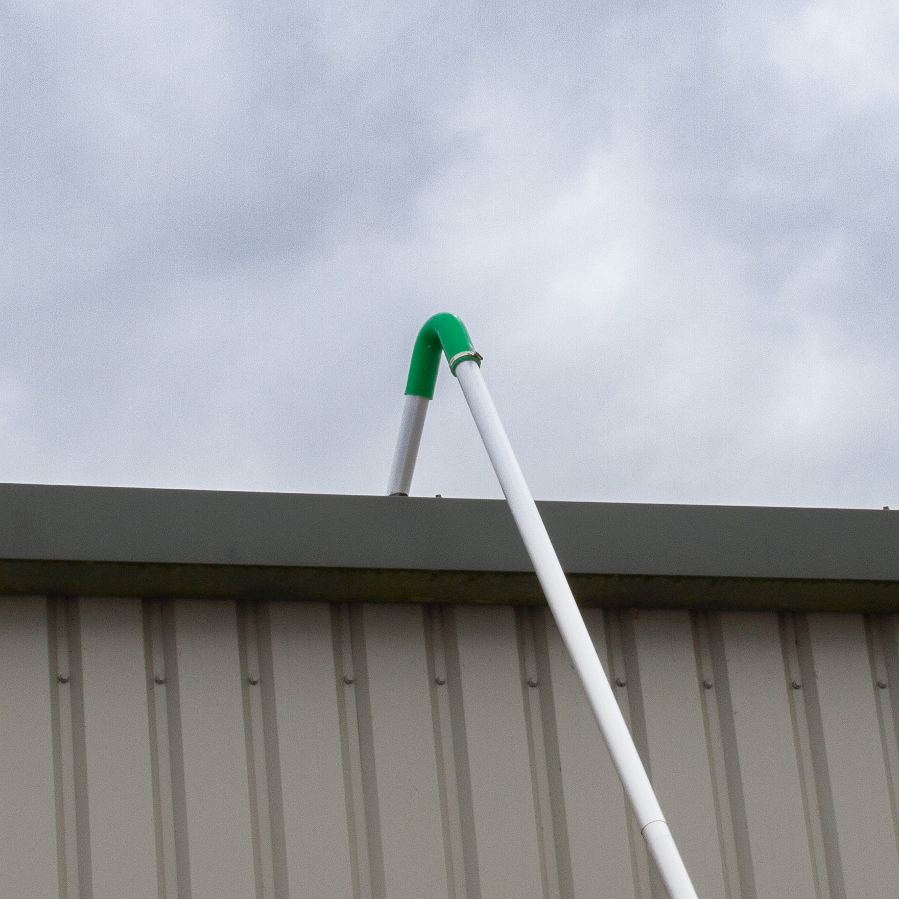 Un tubo blanco con extremo verde se extiende sobre un techo metálico.