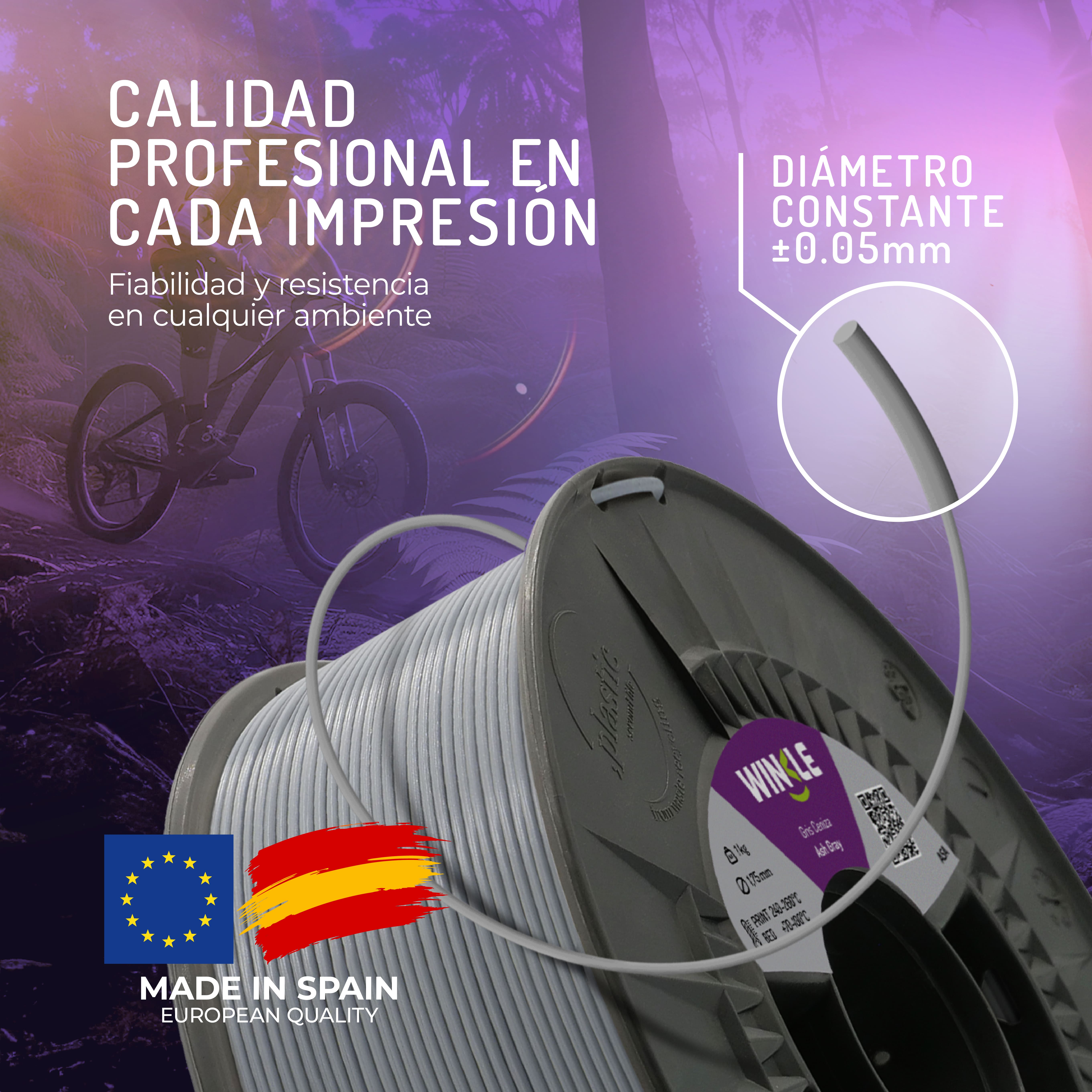 Un carrete de filamento gris para impresora 3D con un ciclista al fondo.